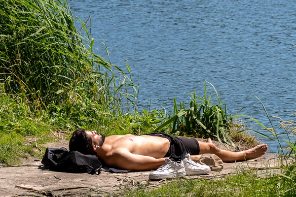 Man ligt te zonnebaden aan het Blauwe Meertje in natuur- en recreatiegebied De IJzeren Man