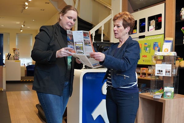 Medewerker van VVV Roermond helpt een klant door iets op de kaart te laten zien